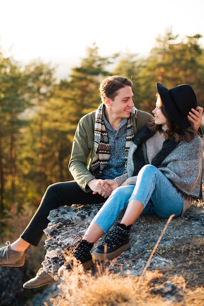 Pareja joven sentada en una roca al aire libre