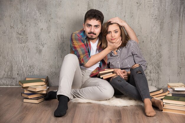 pareja joven sentada en el suelo con libros