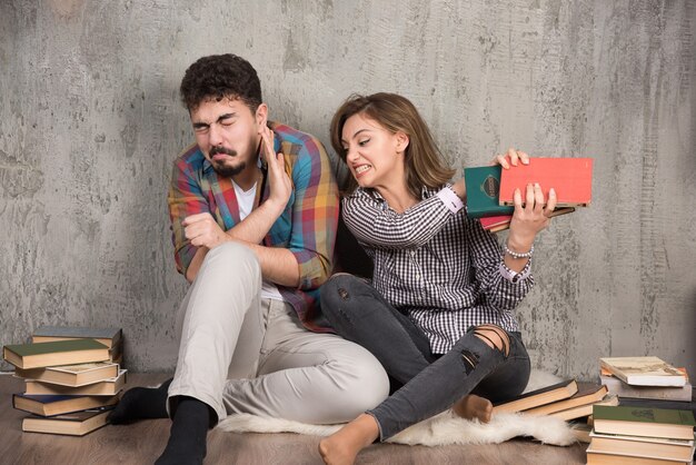 pareja joven sentada en el suelo con libros