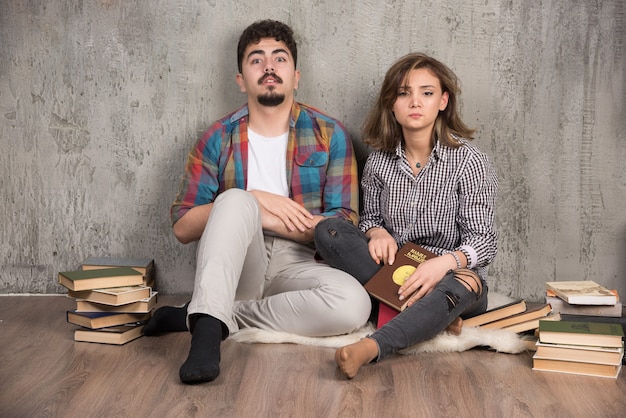 pareja joven sentada en el suelo con libros