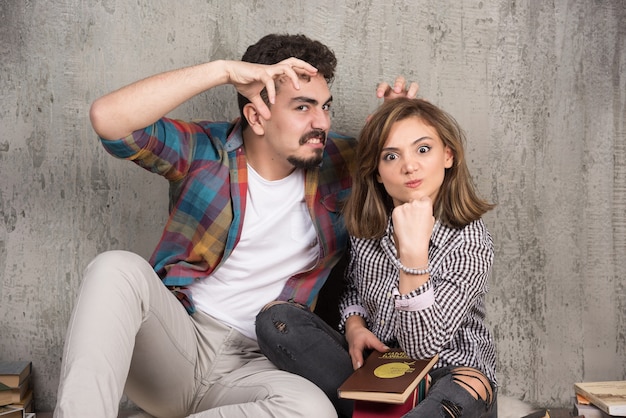 Foto gratuita pareja joven sentada en el suelo con libros