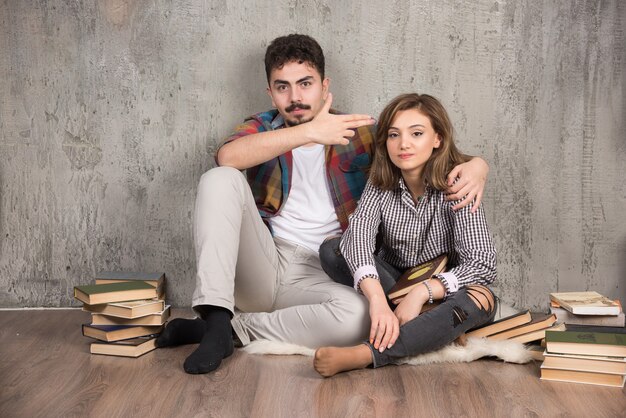 pareja joven sentada en el suelo con libros