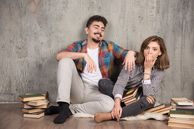 pareja joven sentada en el suelo con libros