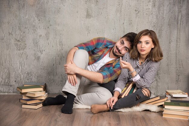 pareja joven sentada en el suelo con libros