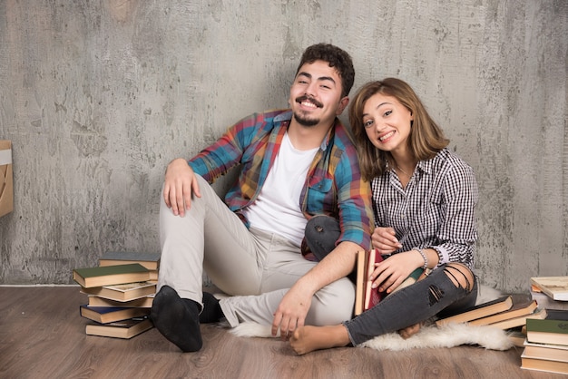 pareja joven sentada en el suelo con libros