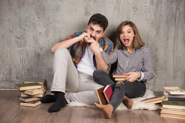 pareja joven sentada en el suelo con libros