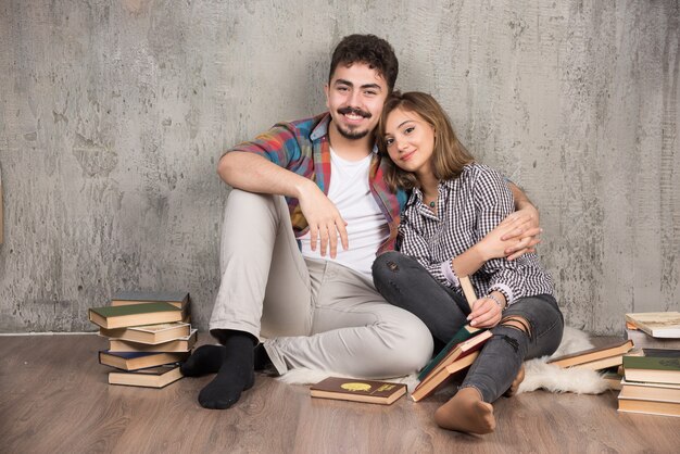 pareja joven sentada en el suelo con libros