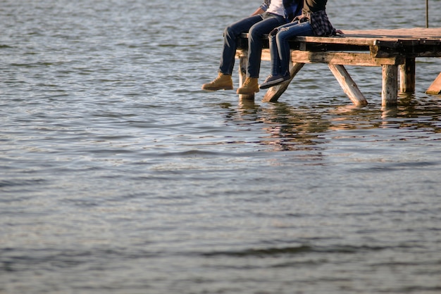 Pareja joven sentada en las tablas del embarcadero