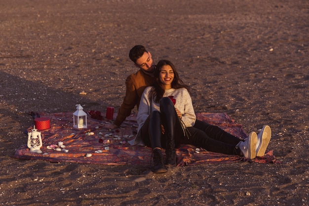 Pareja joven, sentado, en, coverlet, en, orilla de mar