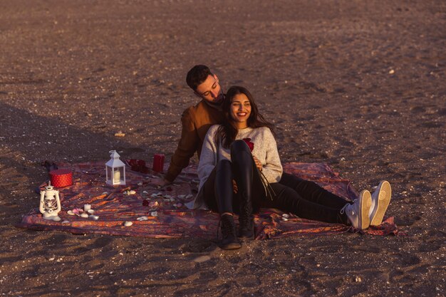 Pareja joven, sentado, en, coverlet, en, orilla de mar