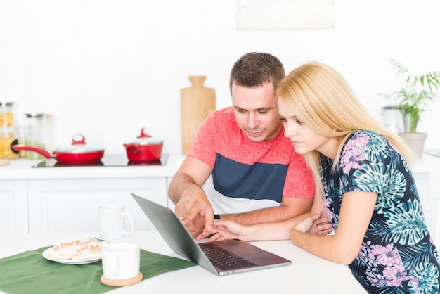 Pareja joven sentados juntos usando la computadora portátil