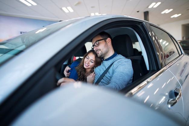 Pareja joven sintiéndose sano y salvo en su coche nuevo