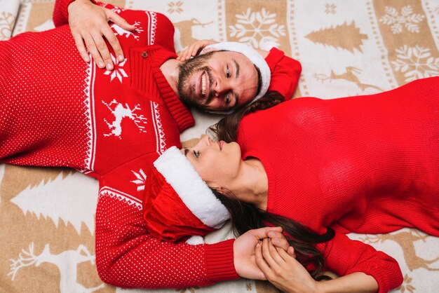 Pareja joven en sombreros de Navidad en tela escocesa