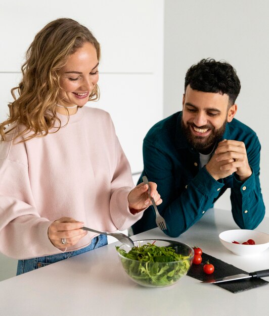 Pareja joven sonriente cocinar juntos en casa