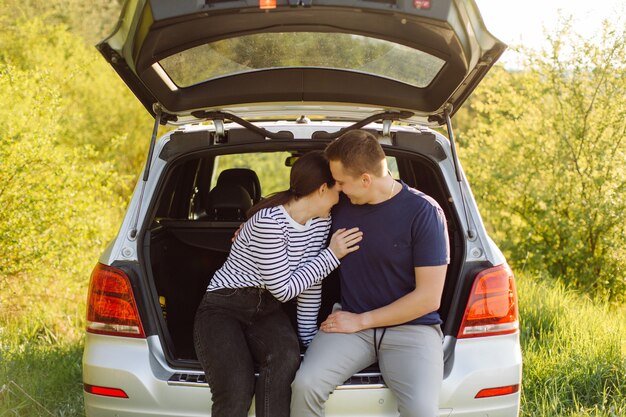 Pareja joven sonriente dentro de un coche. Besos en el coche