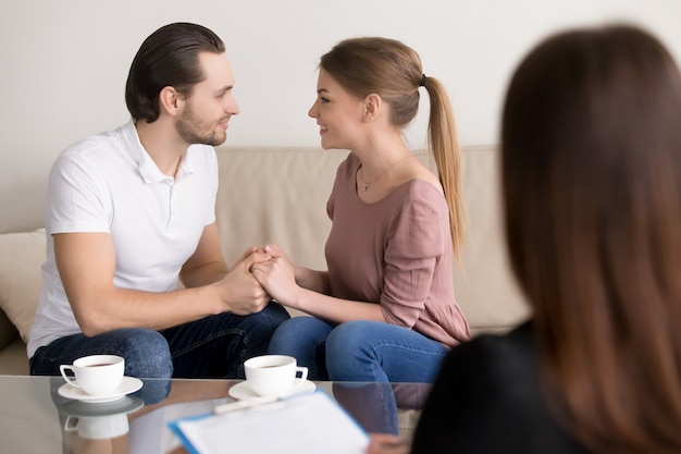 Pareja joven sonriente feliz que lleva a cabo las manos, psicólogo asesor, planeando la boda