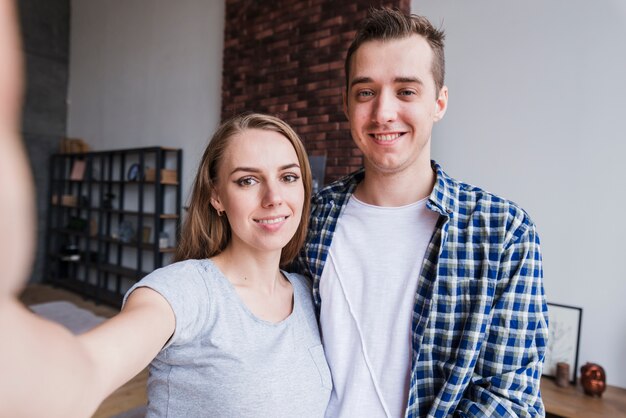 Pareja joven sonriente haciendo selfie en casa