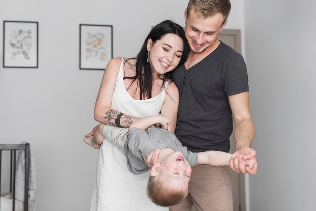 Pareja joven sonriente jugando con su hijo en casa