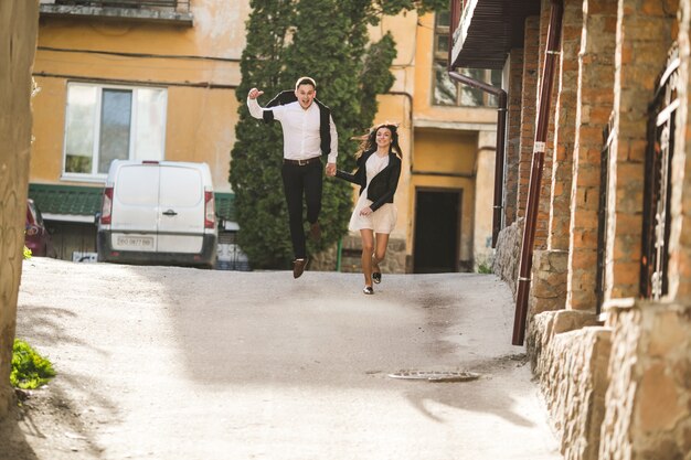 Pareja joven sonriente saltando en la calle