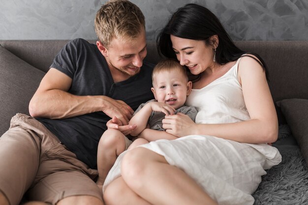 Pareja joven sonriente sentada con su niño encantador