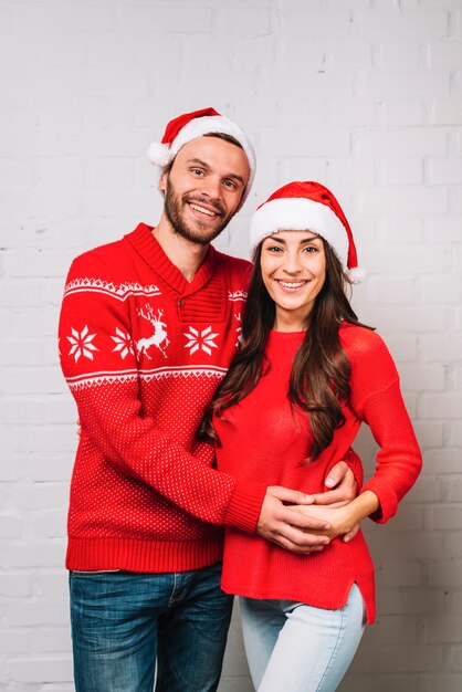 Pareja joven sonriente en sombreros de fiesta