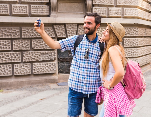 Pareja joven sonriente tomando selfie en teléfono móvil