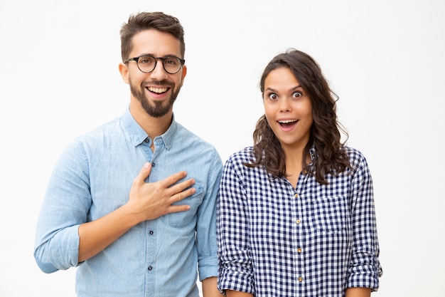 Pareja joven sorprendida mirando a cámara