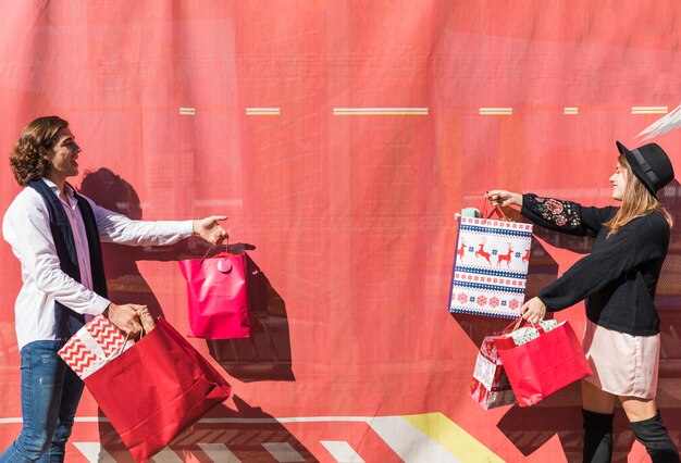 Pareja joven sosteniendo bolsas de compras