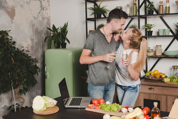 Pareja joven sosteniendo la flauta de champán de pie detrás del mostrador de la cocina