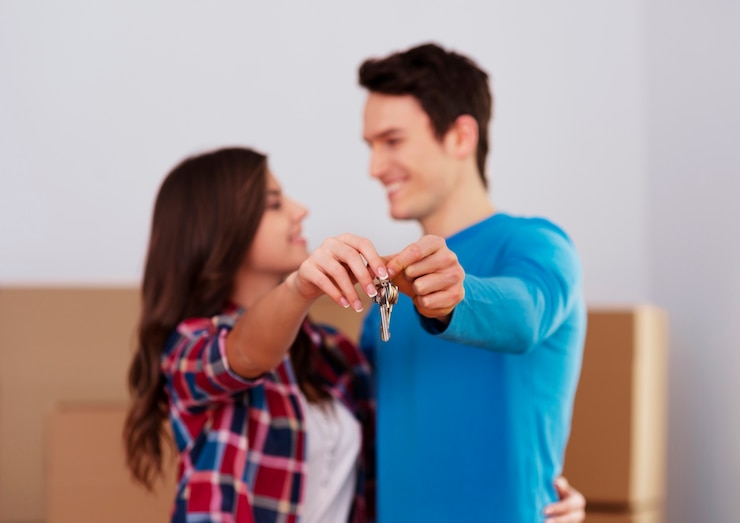 Foto gratuito pareja joven sosteniendo la llave al nuevo hogar en la mano