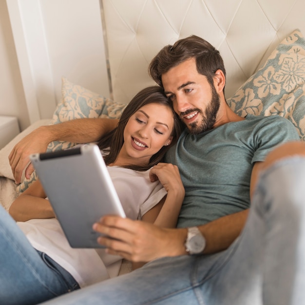 Foto gratuita pareja joven con tableta en la cama