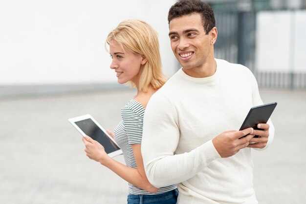 Pareja joven con tabletas al aire libre