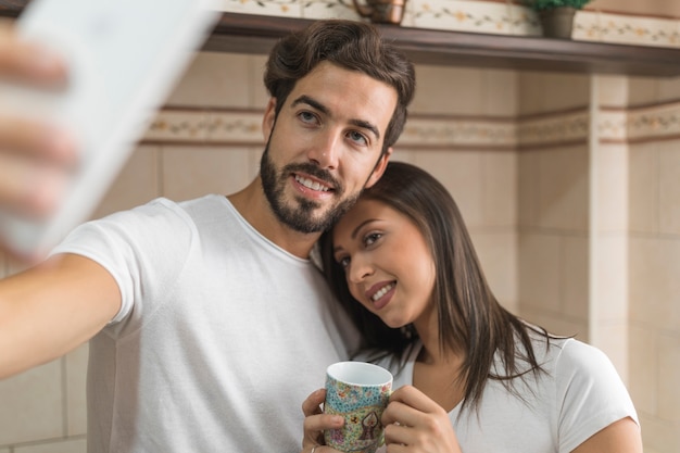 Pareja joven con taza tomando selfie