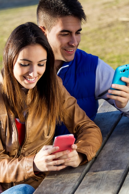 Pareja joven con teléfonos inteligentes en el parque