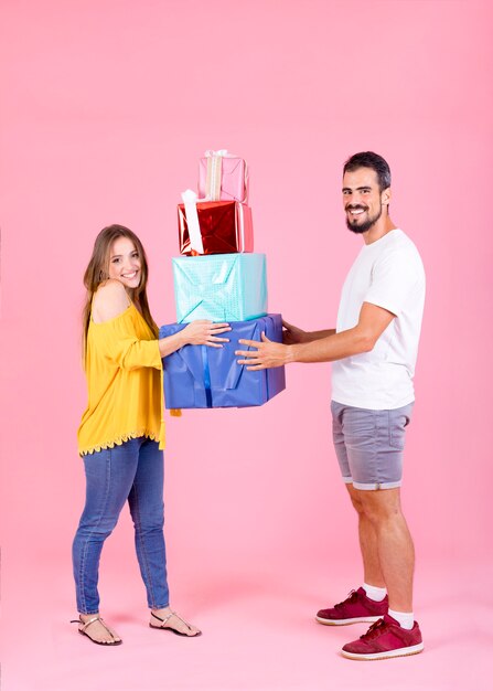 Pareja joven, tenencia, regalo colorido, cajas, contra, rosa, fondo