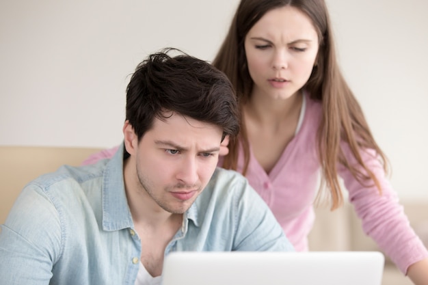 Pareja joven teniendo problemas usando una computadora portátil, mirando frustrado