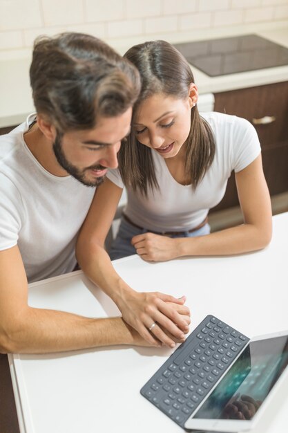 Pareja joven tocando las manos cerca de la tableta