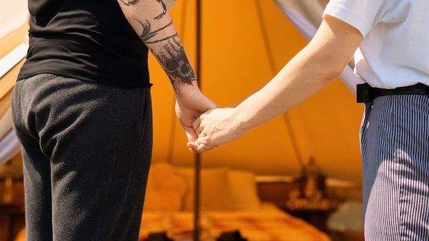 Foto gratuita pareja joven tomados de la mano cerca de la carpa en glamping, cerrar