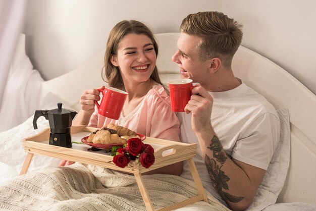 Pareja joven tomando café en la cama