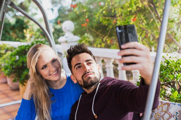 Pareja joven tomando selfie en la terraza