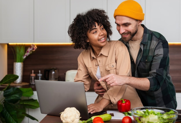 Foto gratuita pareja joven trabajando en la computadora portátil en la cocina