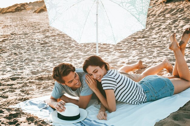 Pareja joven tumbada en la playa