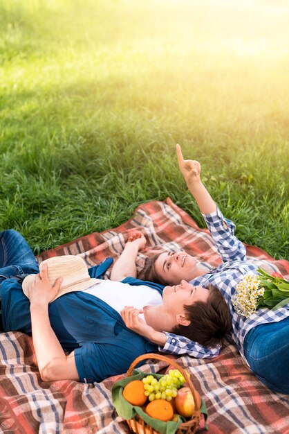 Pareja joven tumbado en la manta y apuntando al cielo