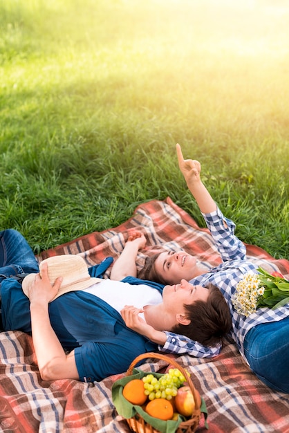 Pareja joven tumbado en la manta y apuntando al cielo