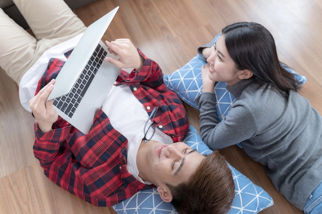 Pareja joven tumbado en el suelo y usando laptop con feliz