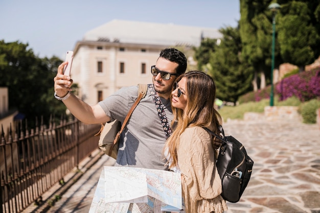 Pareja joven en vacaciones tomando autorretrato con teléfono celular