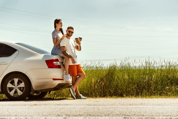 Pareja joven viajando en coche en día soleado