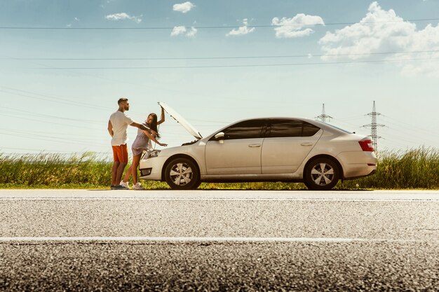 Pareja joven viajando en coche en día soleado