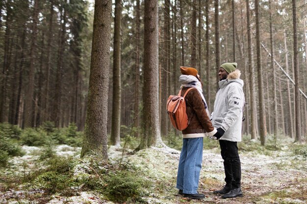 Pareja joven en un viaje por carretera de invierno juntos caminando por el bosque
