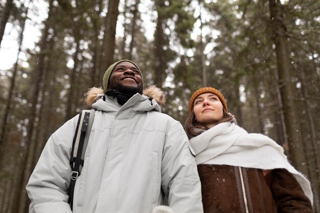 Pareja joven en un viaje por carretera de invierno juntos caminando por el bosque